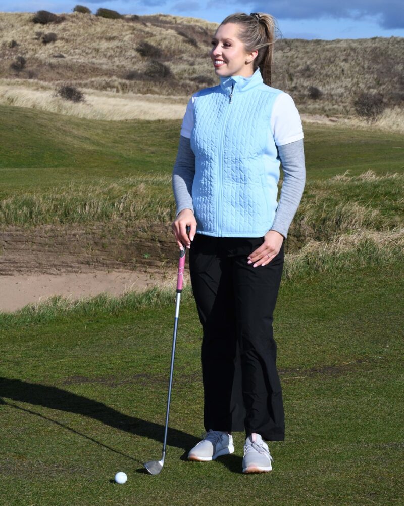 A lady golfer wearing a black ProQuip ProFlex quilted gilet