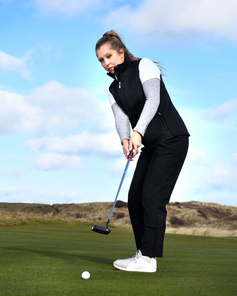 A blonde lady golfer wearing a black ProQuip ProFlex quilted gilet