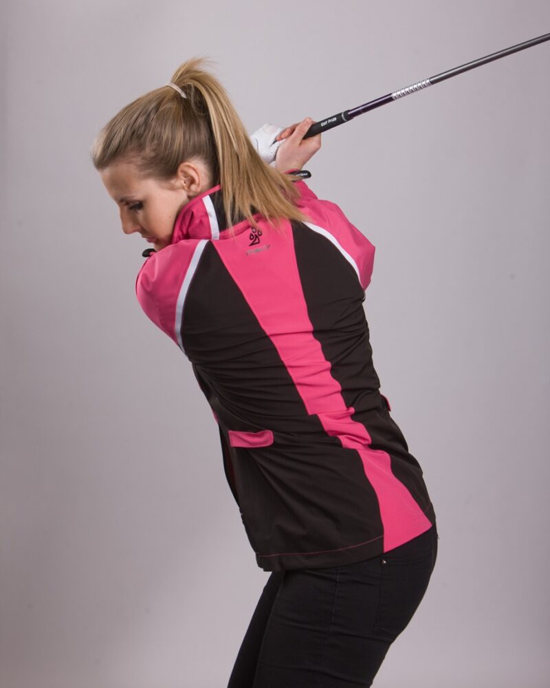 A blonde-haired, blue eyed, lady golfer wearing a ProQuip ProFlex Ladies golf rain jacket